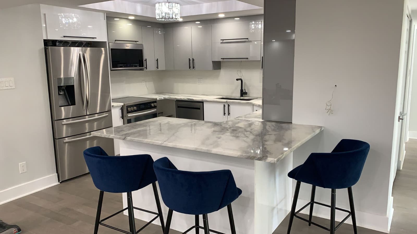 Cuisine gris laqué en U avec comptoir en quartz gris et tabourets bleu marine