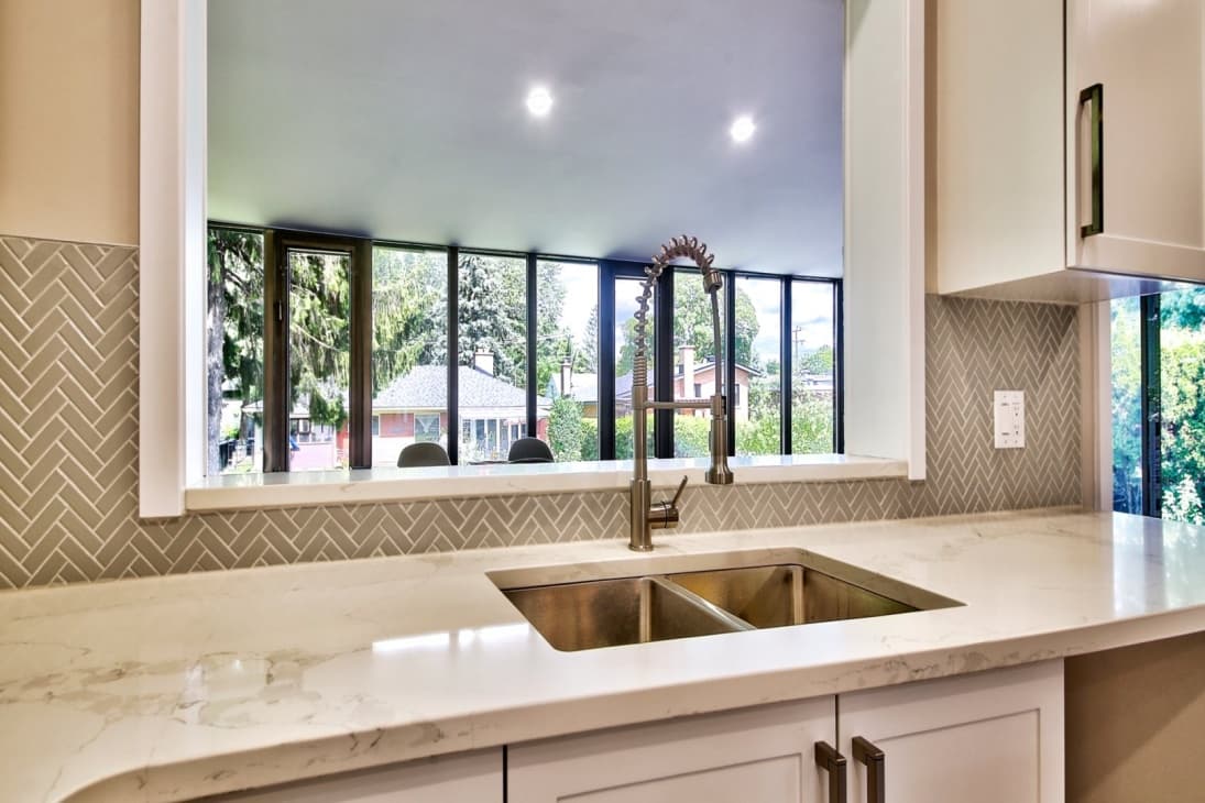 Détail évier en quartz blanc avec dosseret en chevron et fenêtres panoramiques